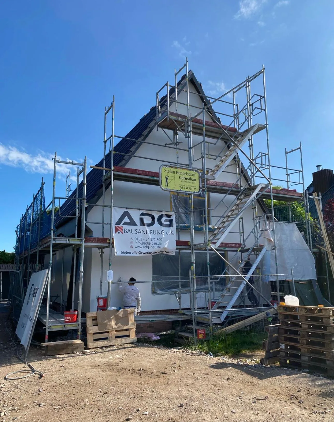 Eingerüstetes Wohnhaus während Bauarbeiten mit ADG Bausanierung Banner